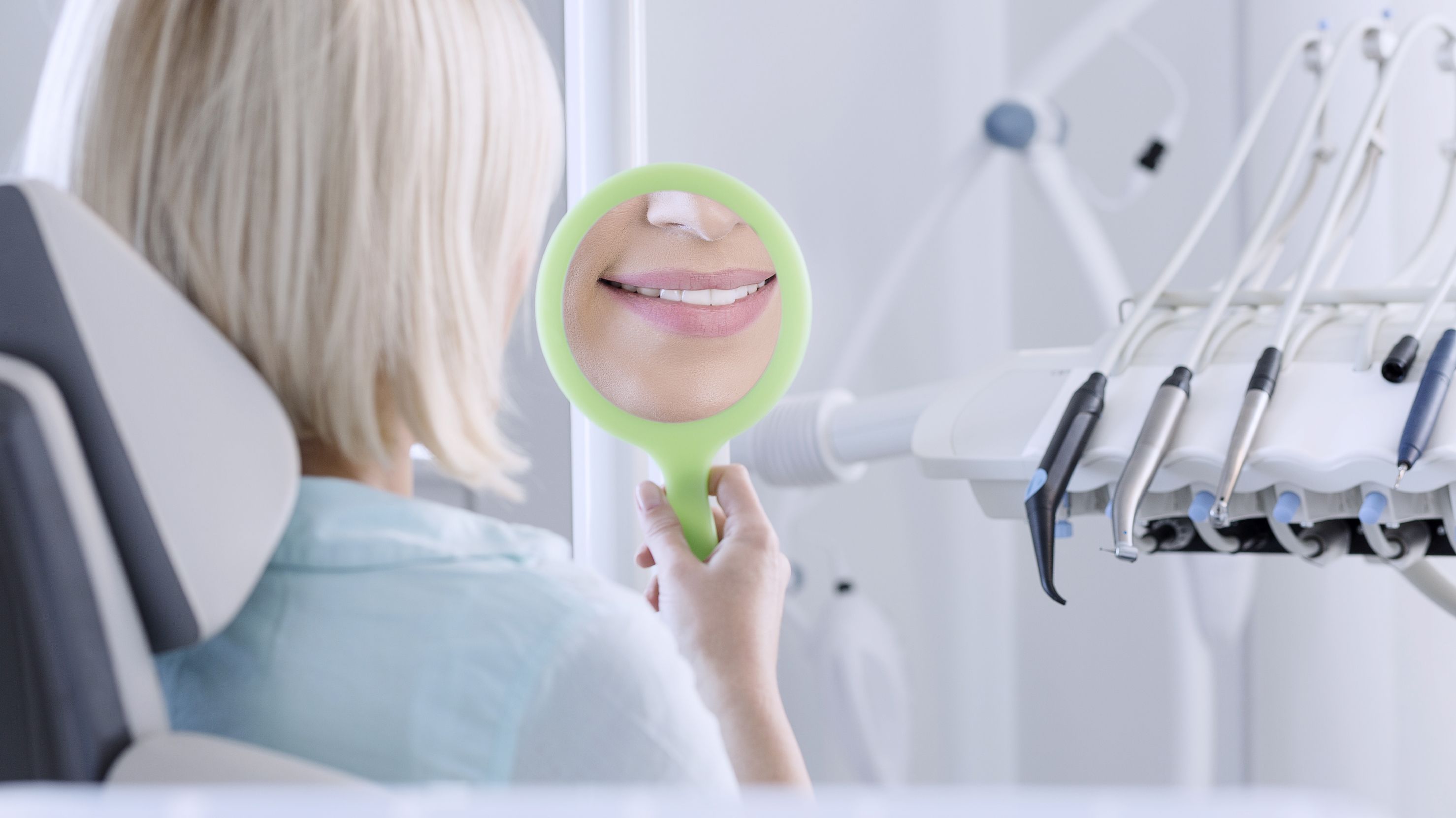 A woman looks at her reflection with a handheld mirror